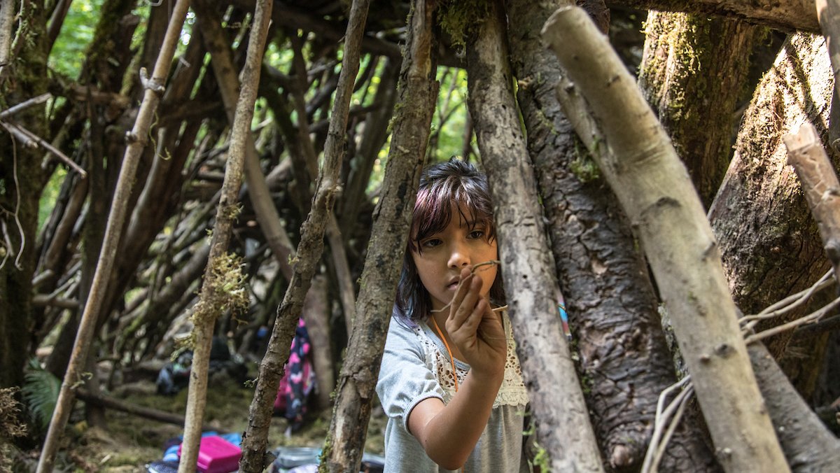 Child in a makeshift wooden structure an outdoor summer camp