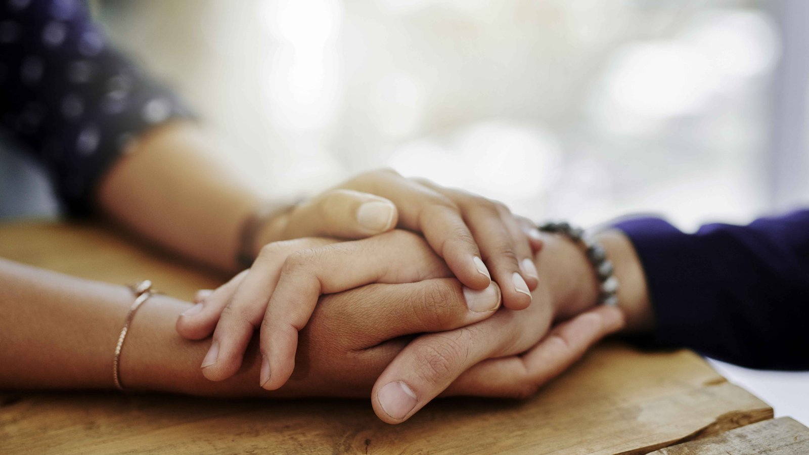 Closeup of two people holding hands in a comforting manner