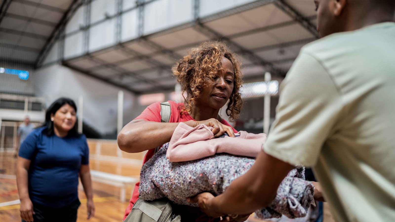 Volunteers in a gymnasium or other large space with a stack of blankets