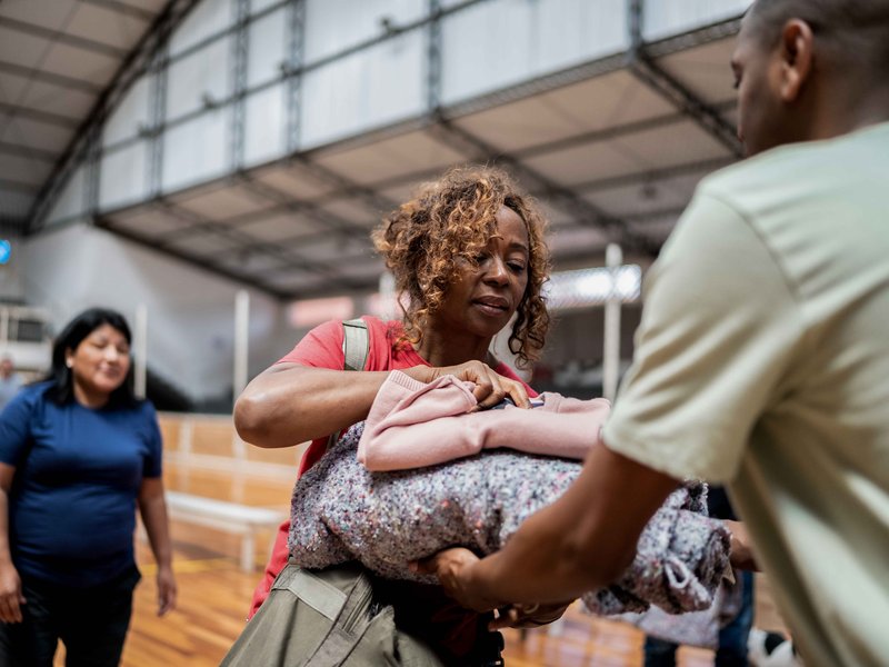 Volunteers in a gymnasium or other large space with a stack of blankets