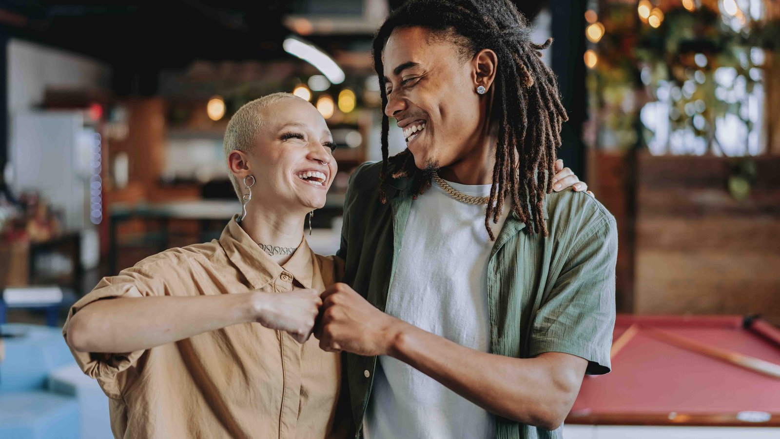 Two black business owners — an older woman and a young man — smiling and fist-bumping in a restaurant or bar