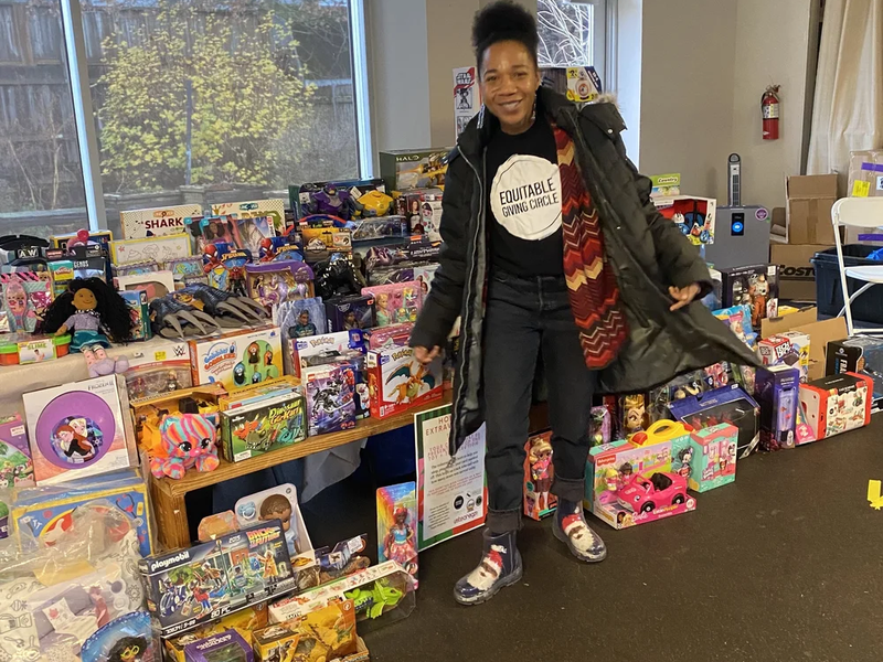 Woman in Equitable Giving Circle t-shirt in front of a large display of toys and games