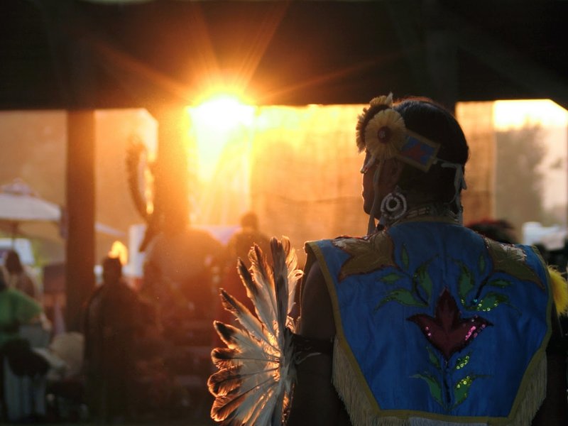 Male dancer in Native dance regalia, facing the sunset