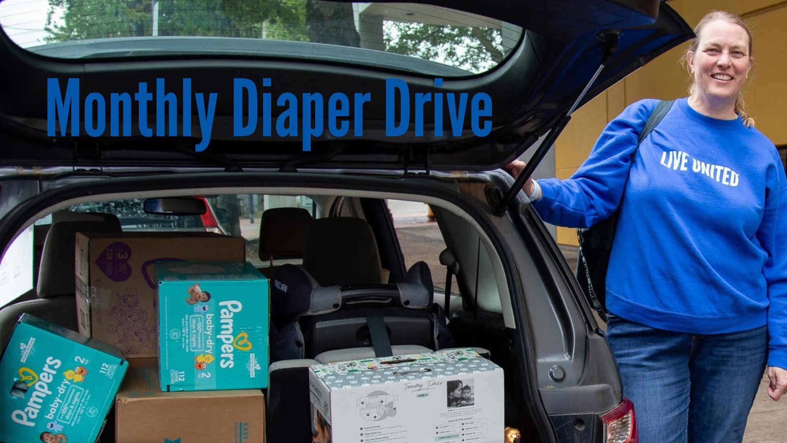 Photo of a person in a blue LIVE UNITED sweatshirt, standing next to an open car trunk full of boxes of diaper