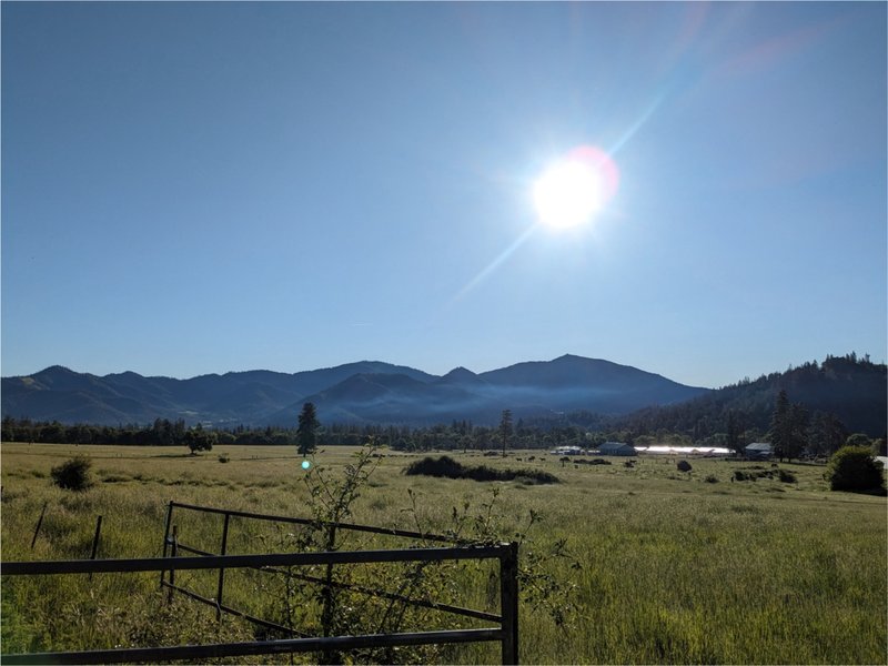 Broad valley under sunny skies with a thin layer of wildfire smoke in the distance