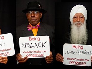 People holding signs reading “Being [Black, brown, Sikh, two-spirit, etc.] doesn’t make me dangerous”