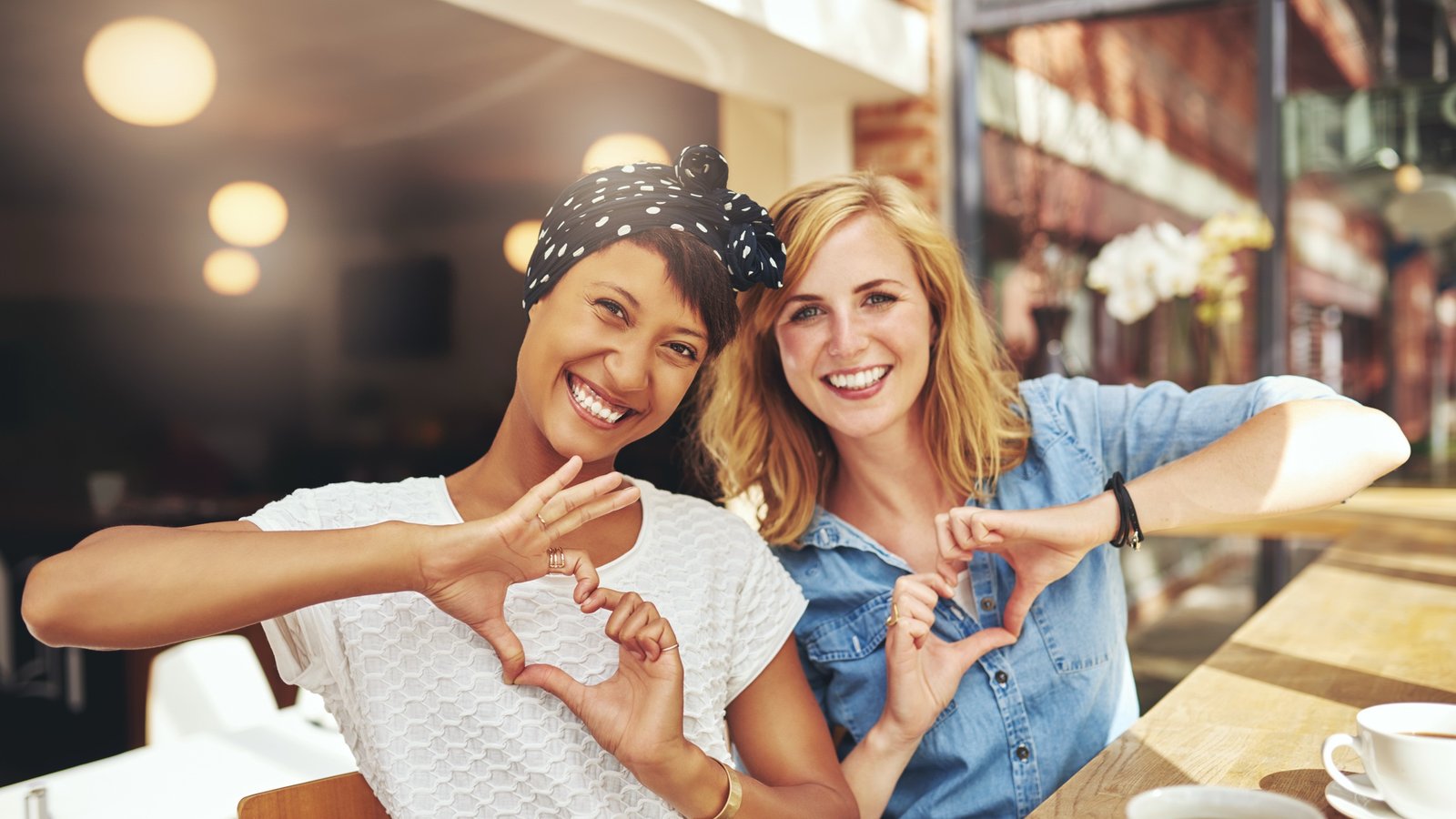 Two young women making “heart” shapes with their hands