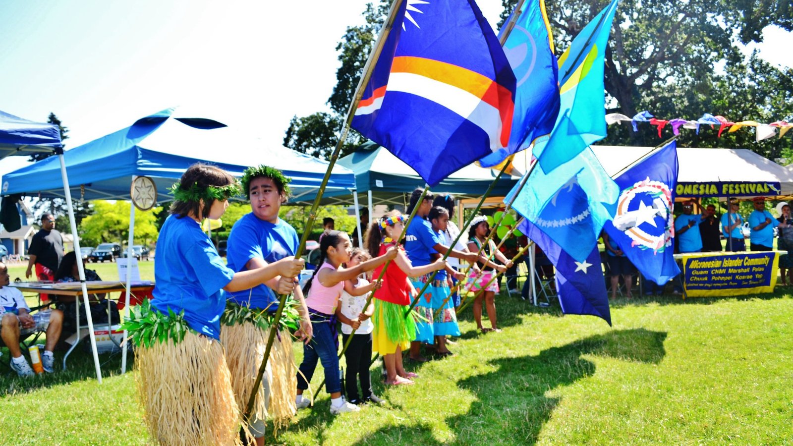 Islanders holding flags of various Pacific Island nations at a gathering