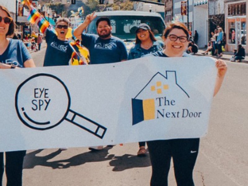 Volunteers for The Next Door in a parade, holding a banner