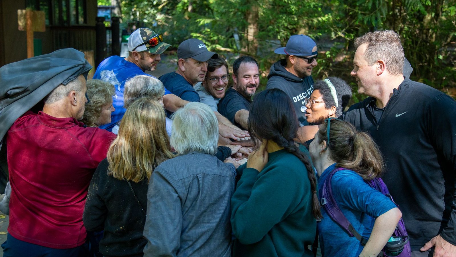 Group of volunteers in a forest doing “all hands in”