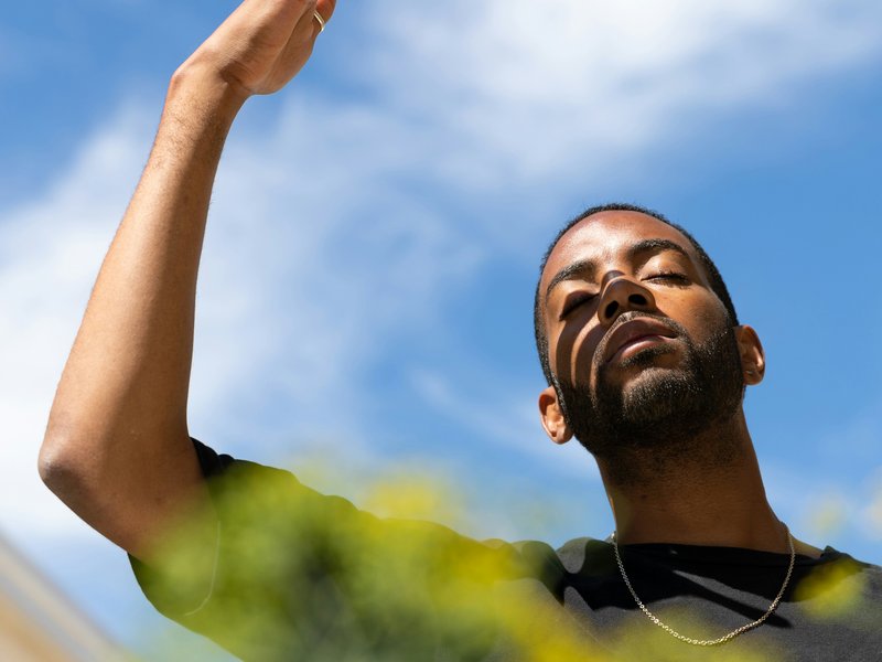 Young Black man shielding his face from the sun