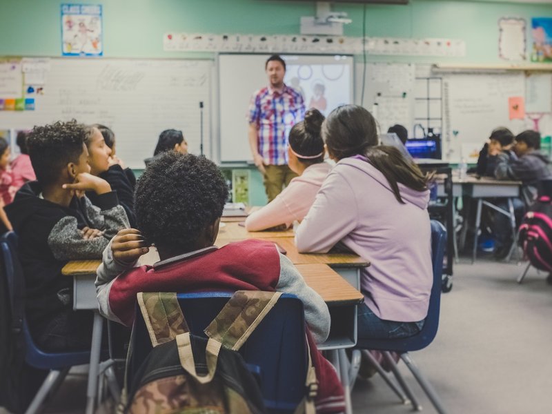 High school classroom, students looking toward a teacher